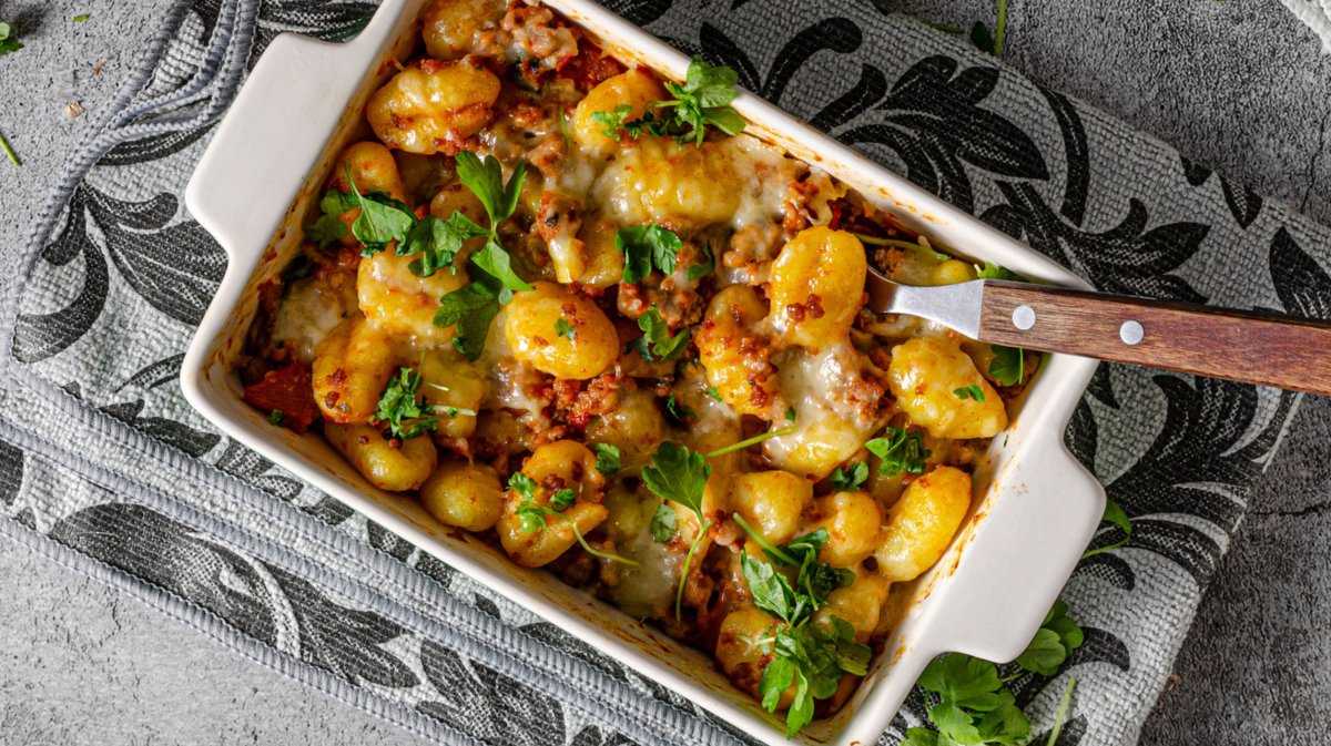 Überbackene Gnocchi mit Käse und Hackfleisch in weißer Auflaufform.