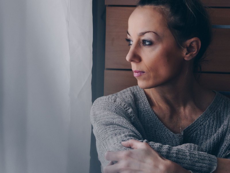 Frau schaut traurig aus dem Fenster