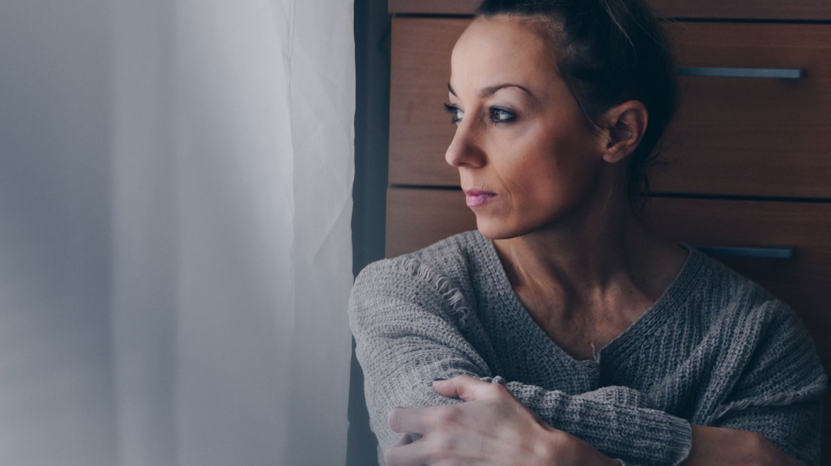 Frau schaut traurig aus dem Fenster