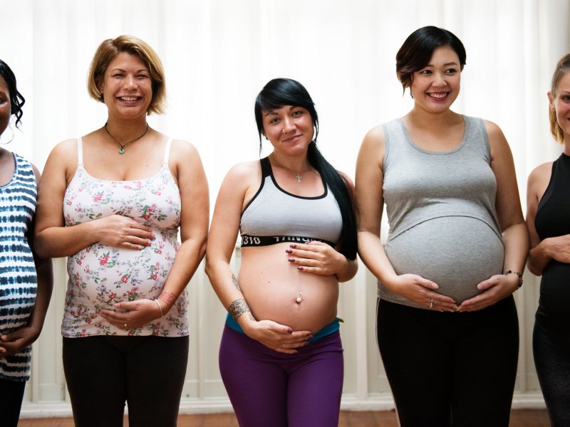 5 schwangere Frauen unterschiedlichen Alters und Ethnie stehen nebeneinander.