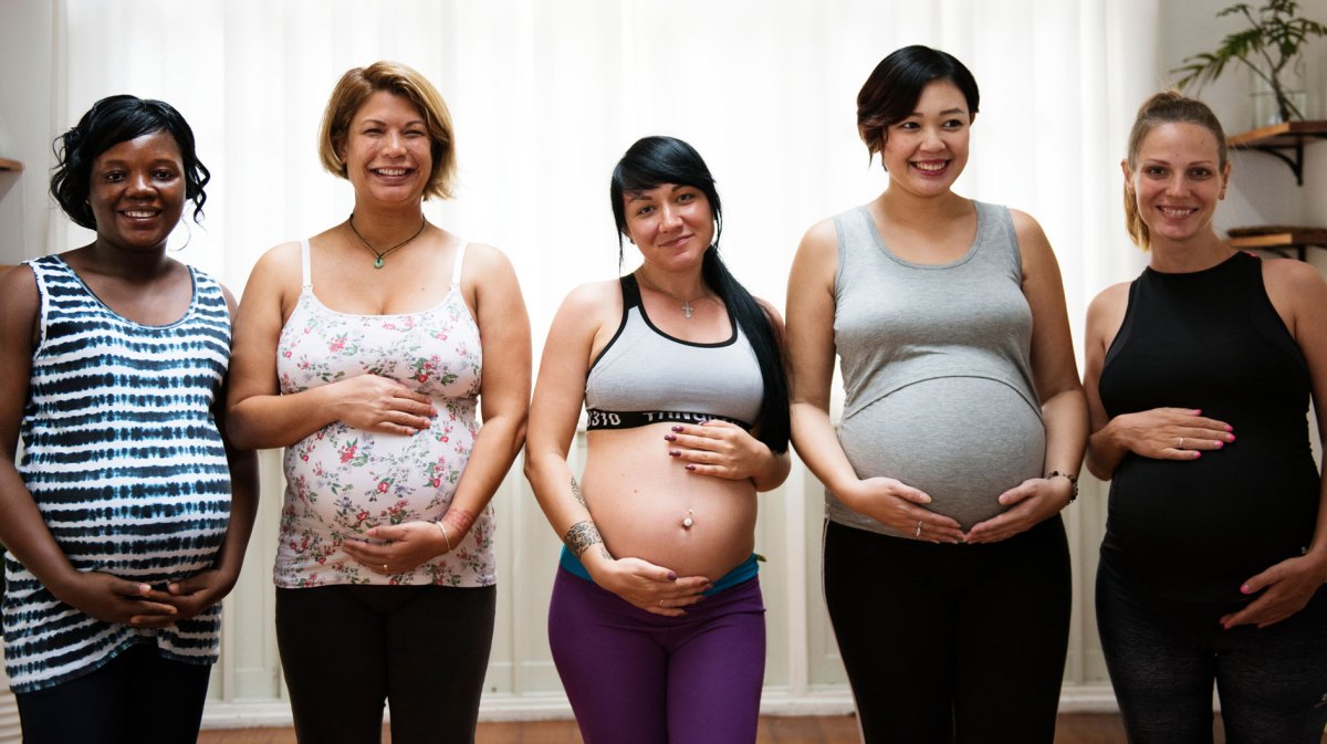 5 schwangere Frauen unterschiedlichen Alters und Ethnie stehen nebeneinander.