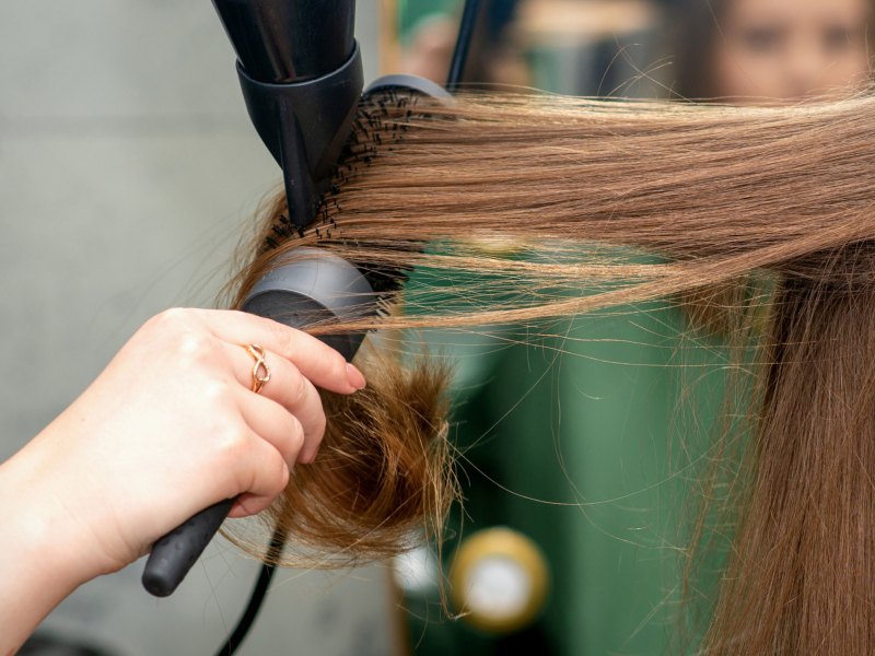 Friseurin föhnt Frau die Haare über eine Rundbürste