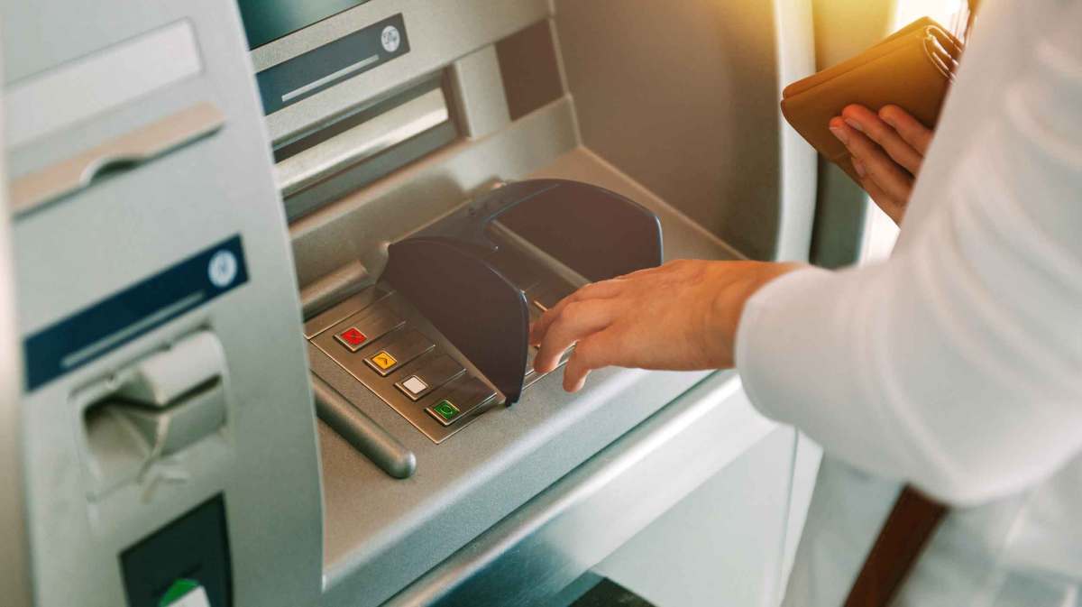 Person hebt Geld von einem Bankautomaten ab.