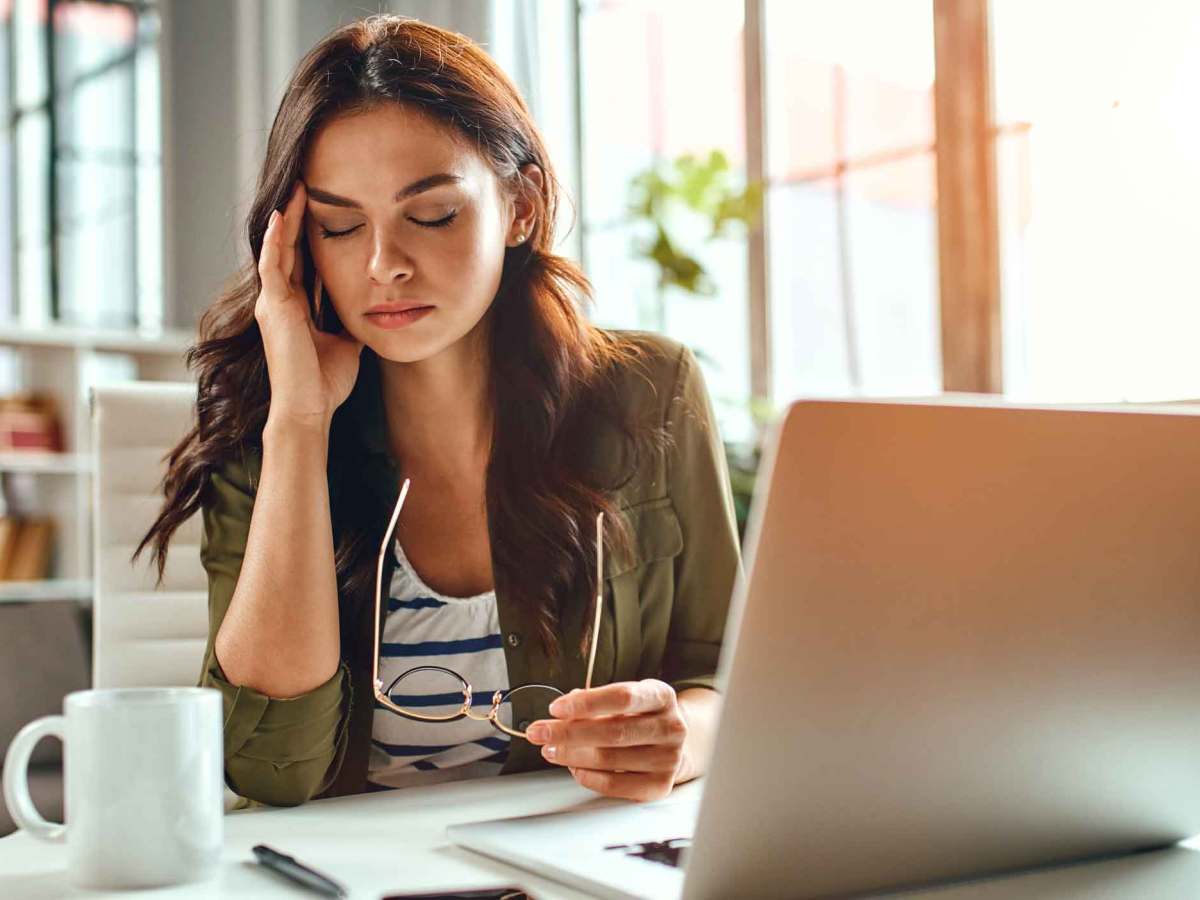 Brünette Frau sitzt vor Laptop.