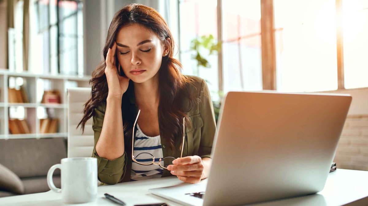 Brünette Frau sitzt vor Laptop.