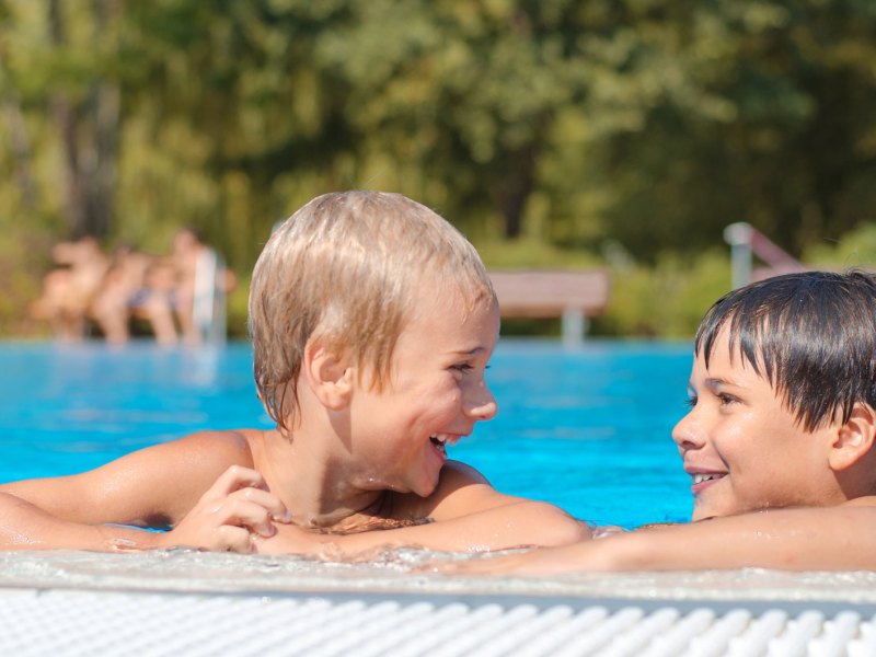 Zwei Jungs, ca. 9 Jahre alt, am Beckenrand im Freibad.