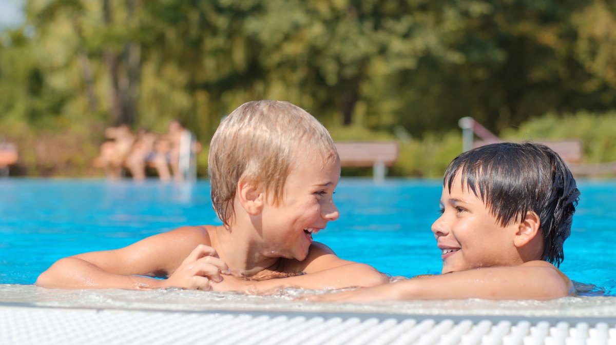 Zwei Jungs, ca. 9 Jahre alt, am Beckenrand im Freibad.