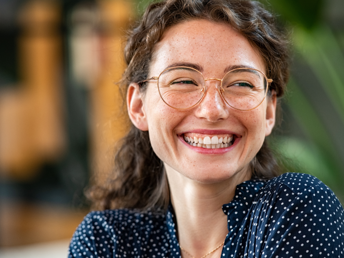 Junge Frau mit Brille lächelt breit.