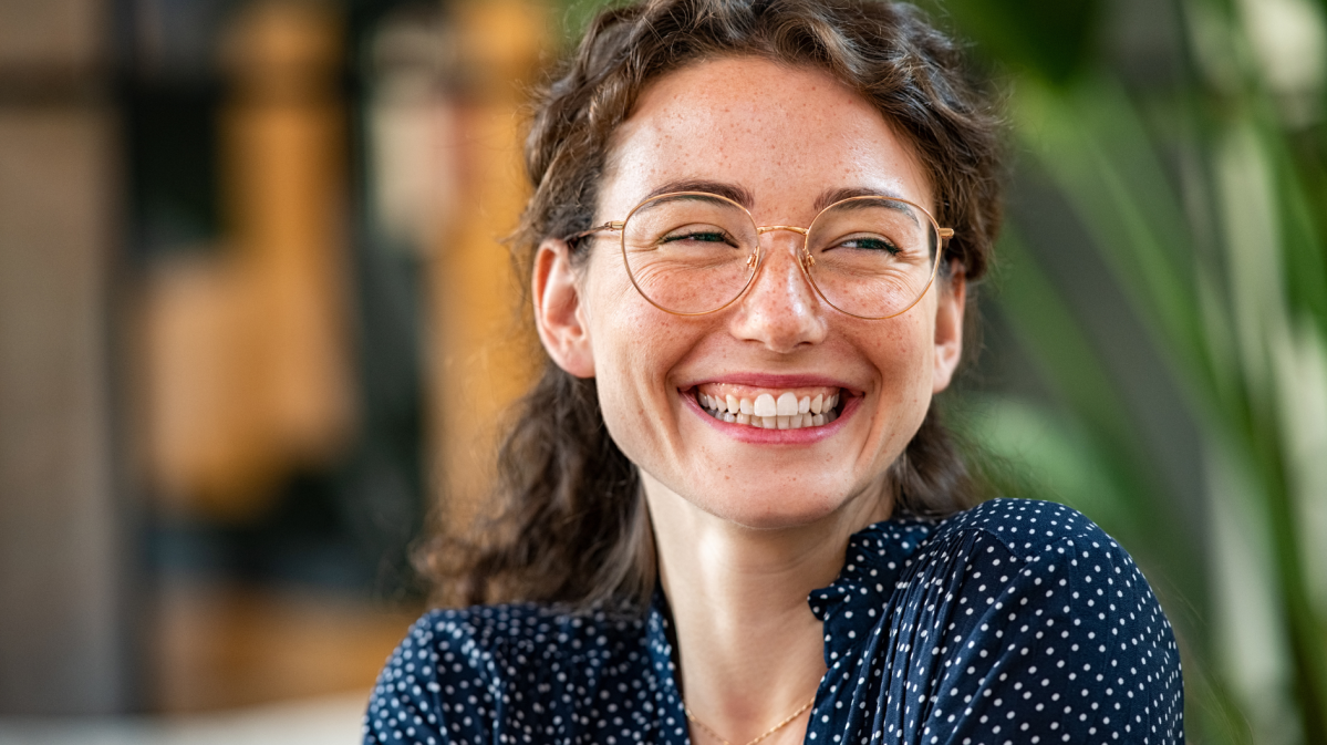 Junge Frau mit Brille lächelt breit.