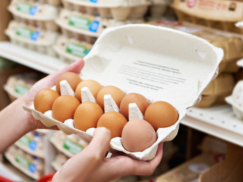 Person schaut im Supermarkt in Eierkarton.