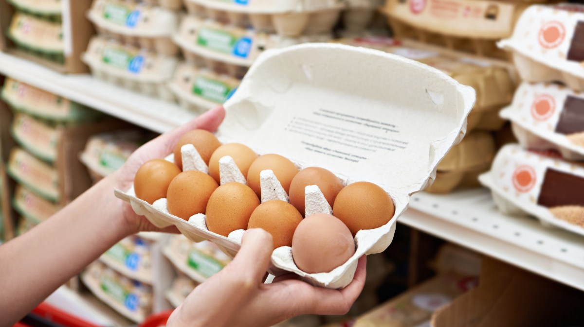 Person schaut im Supermarkt in Eierkarton.