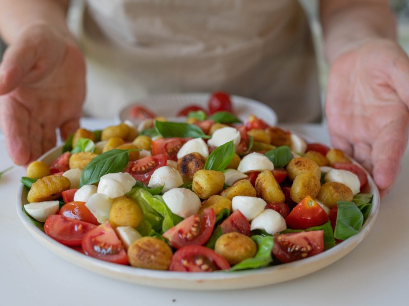 Salat mit Gnocchi, Tomaten, Mozzarella und Basilikum in einer großen Schale.