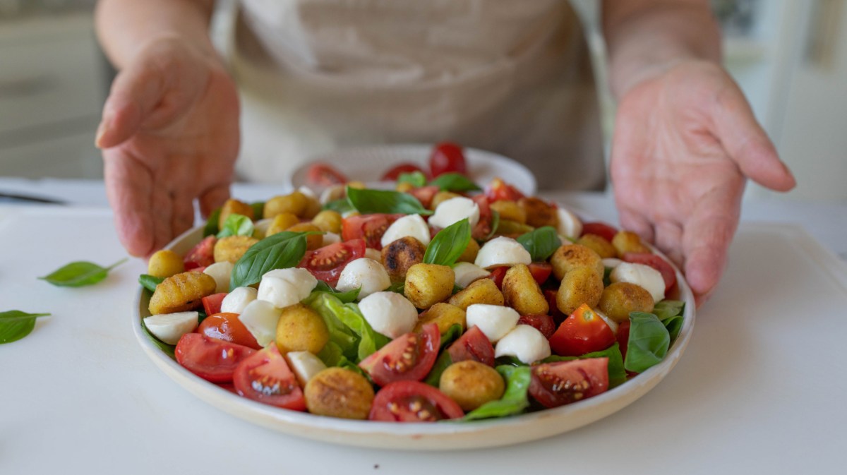 Salat mit Gnocchi, Tomaten, Mozzarella und Basilikum in einer großen Schale.