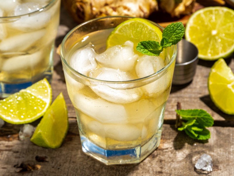 Cocktail mit Ginger Ale, Limette und Eiswürfel in einem kurzen Glas.