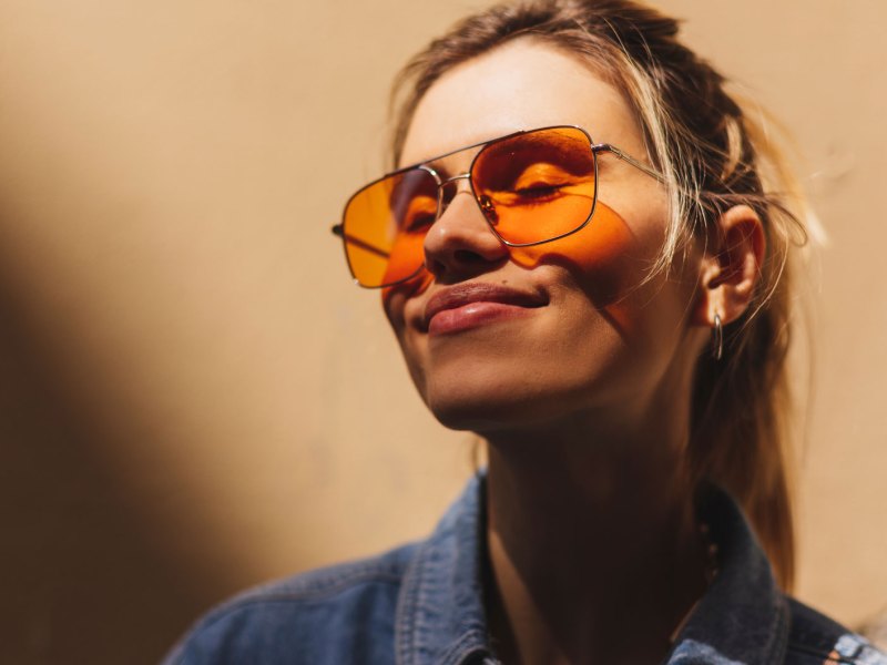 Frau mit orangefarbener Sonnenbrille lächelt