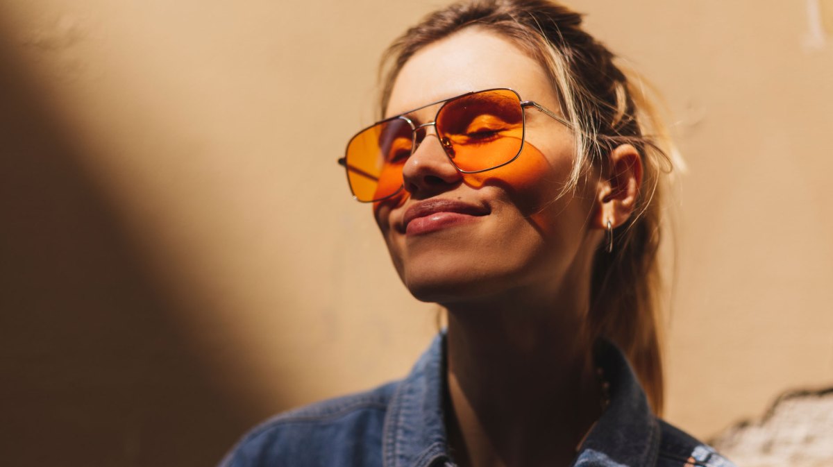 Frau mit orangefarbener Sonnenbrille lächelt