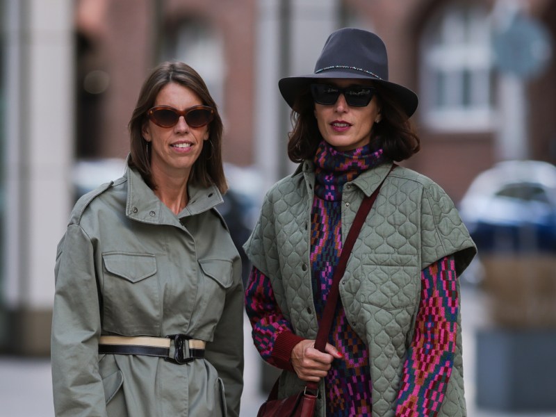 Frauen mit gemusterten Herbst-Kleidern und grünen Jacken im Utility-Stil