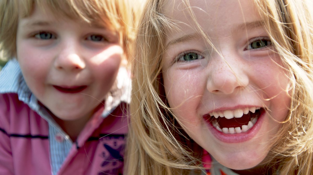 Nahaufnahme zweier Kinder, die in die Kamera strahlen.