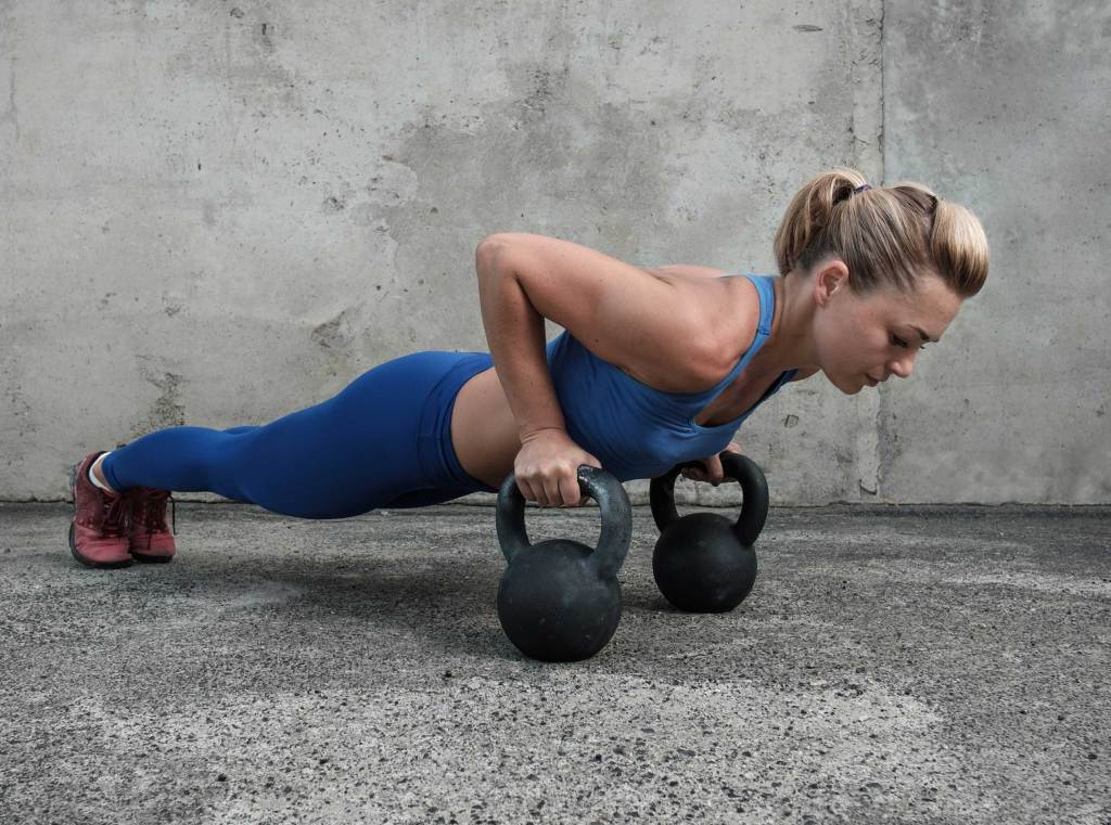 Frau macht Liegestütze mit Kettlebells