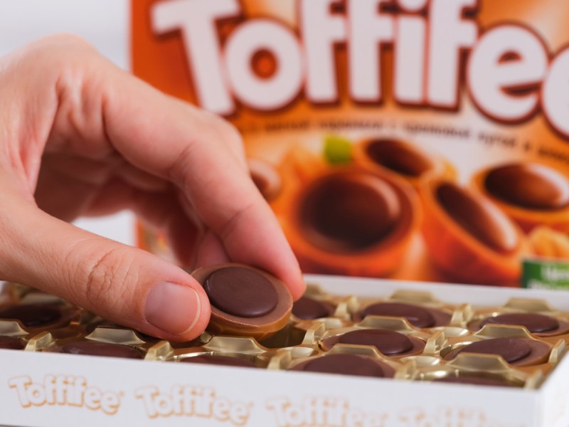 Person mit Toffifee aus Verpackung.