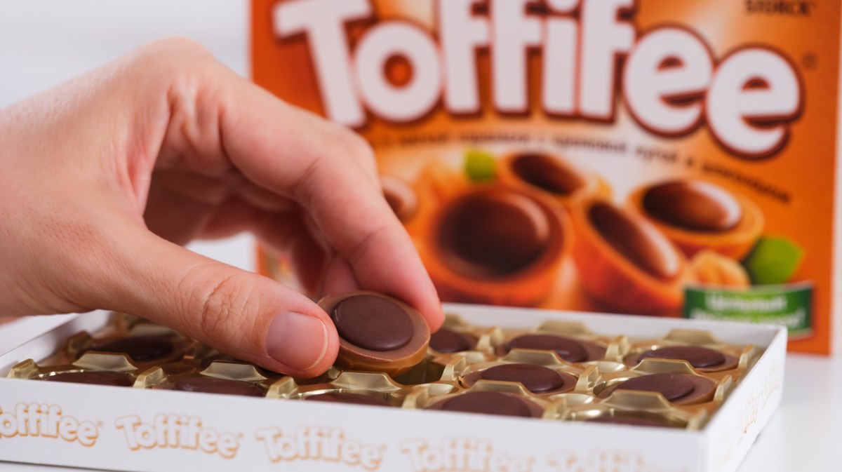 Person mit Toffifee aus Verpackung.