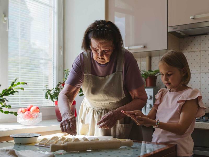 Großmutter und Enkelin, ca. 7 Jahre alt, backen gemeinsam in der Küche.