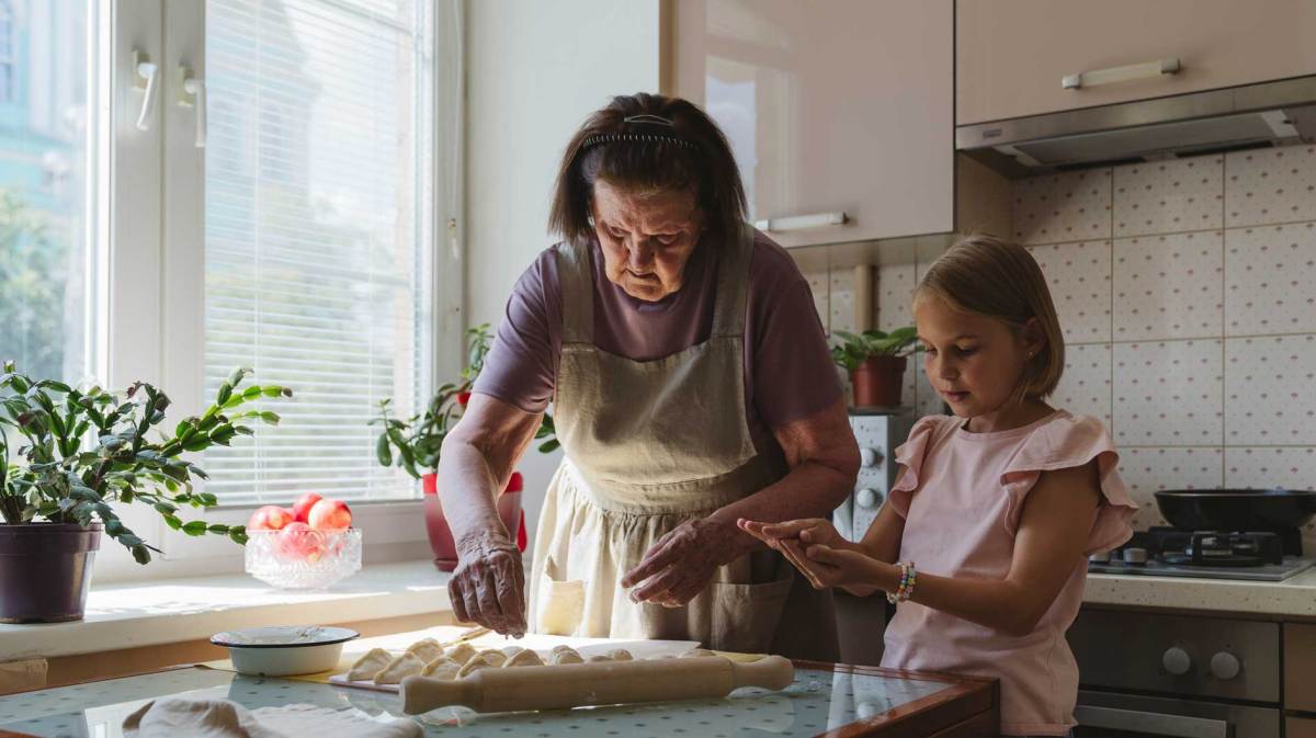 Großmutter und Enkelin, ca. 7 Jahre alt, backen gemeinsam in der Küche.