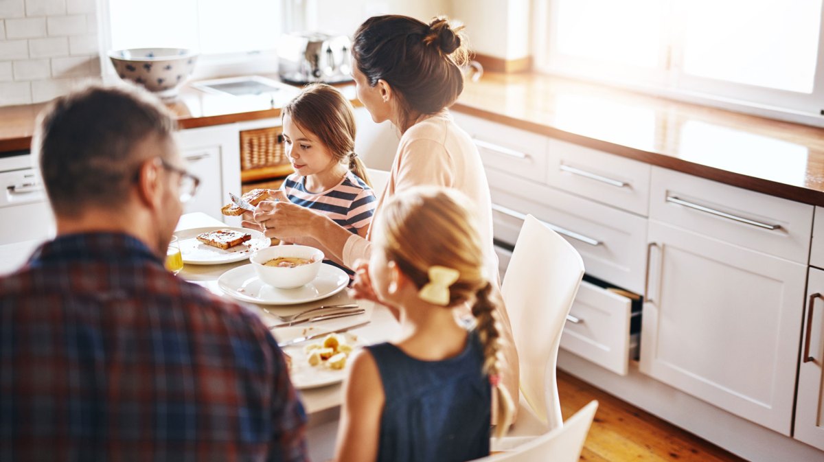 Vierköpfige Familie sitzt gemeinsam am Frühstückstisch.