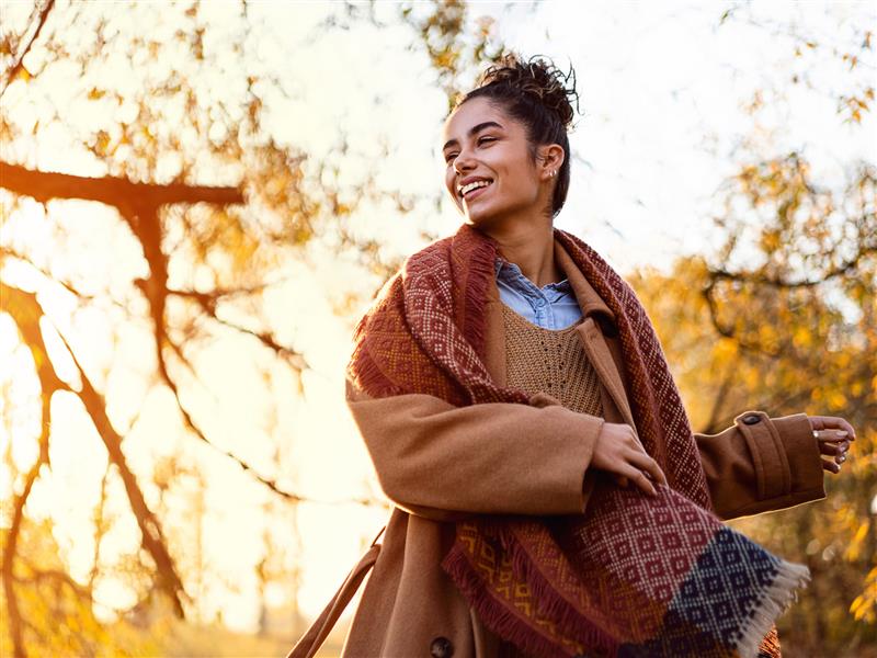 Frau mit Herbstmantel und Schal in herbstlicher Landschaft