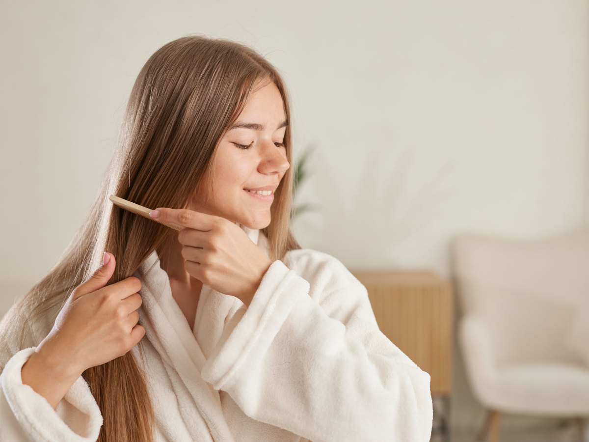 Frau, die sich ihre langen braunen Haare kämmt.