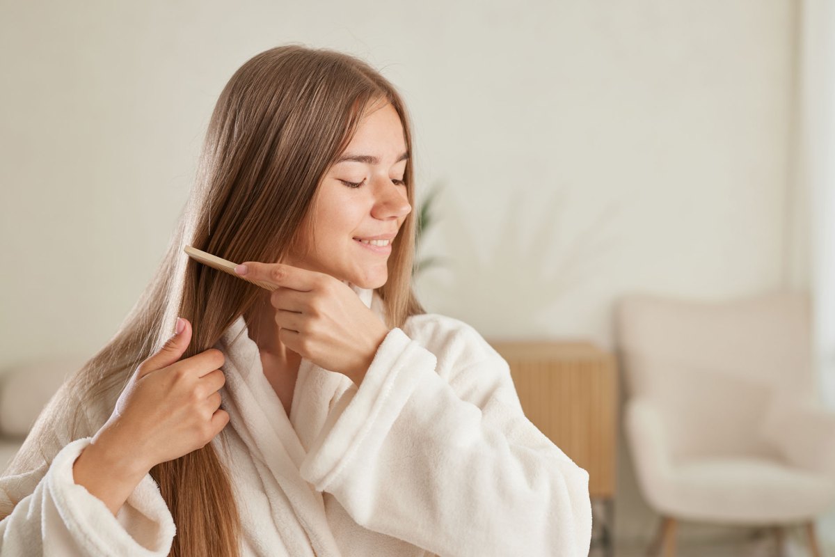 Frau, die sich ihre langen braunen Haare kämmt.