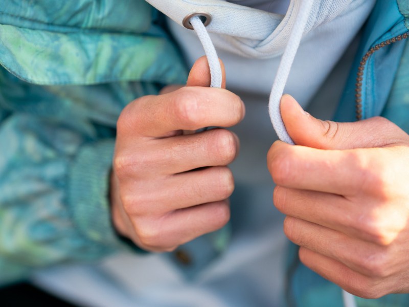 Hände halten Kordel an einem Pullover