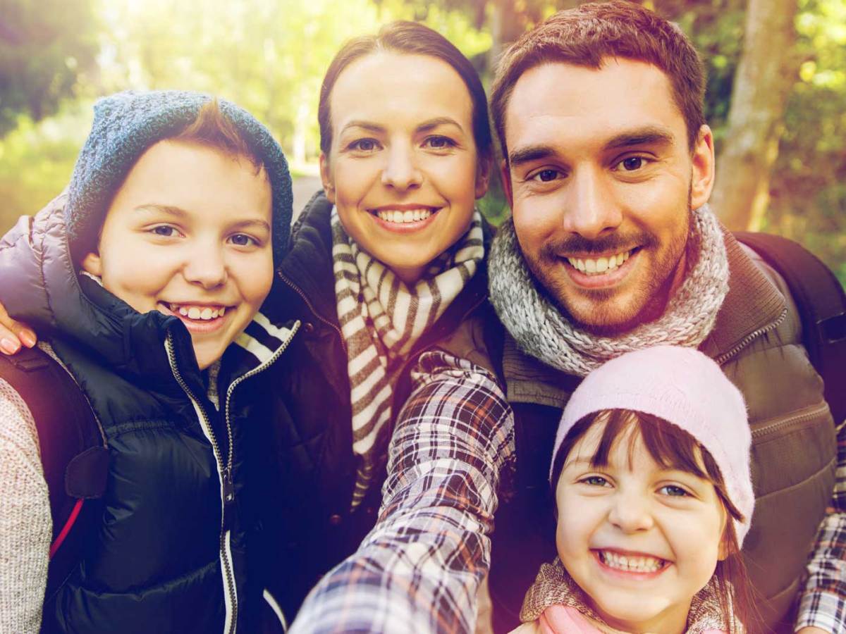 Selfie von Mutter, Vater, Sohn und Tochter bei einer Wanderung im Wald.