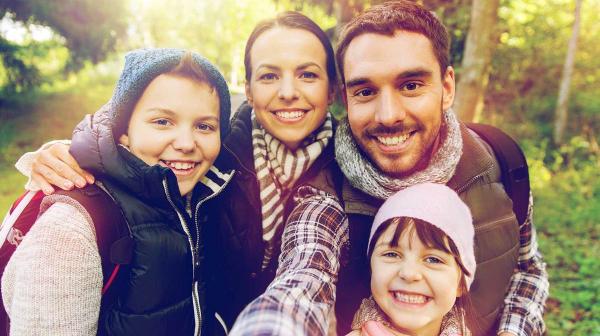 Selfie von Mutter, Vater, Sohn und Tochter bei einer Wanderung im Wald.