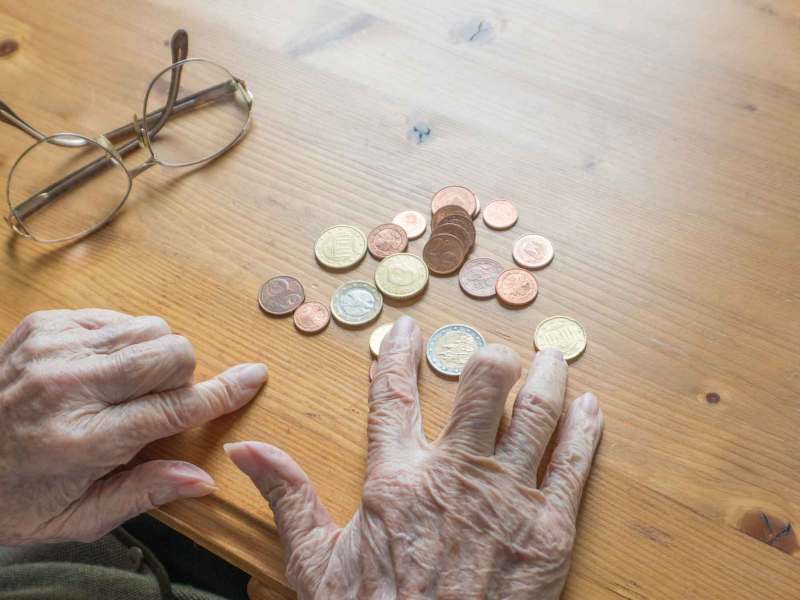 Rentnerin sortiert Kleingeld auf dem Tisch.