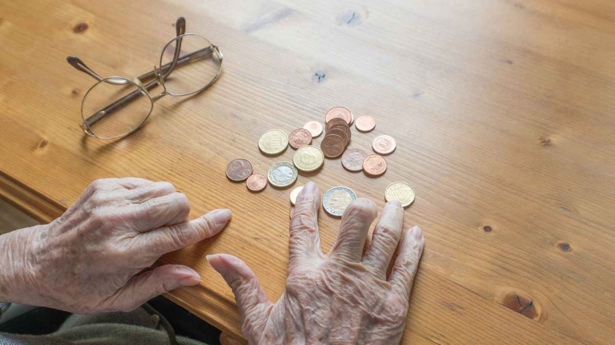 Rentnerin sortiert Kleingeld auf dem Tisch.