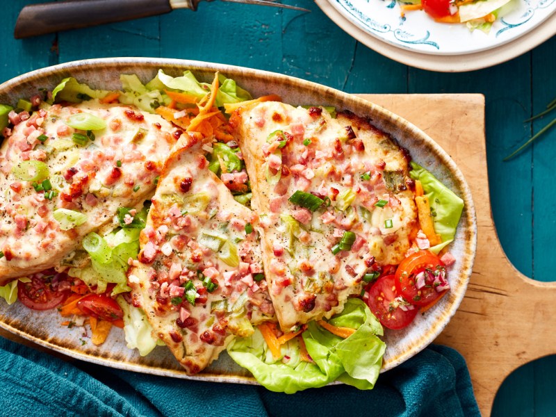 Schnitzel überbacken mit Flammkuchen Topping auf Salatbett.