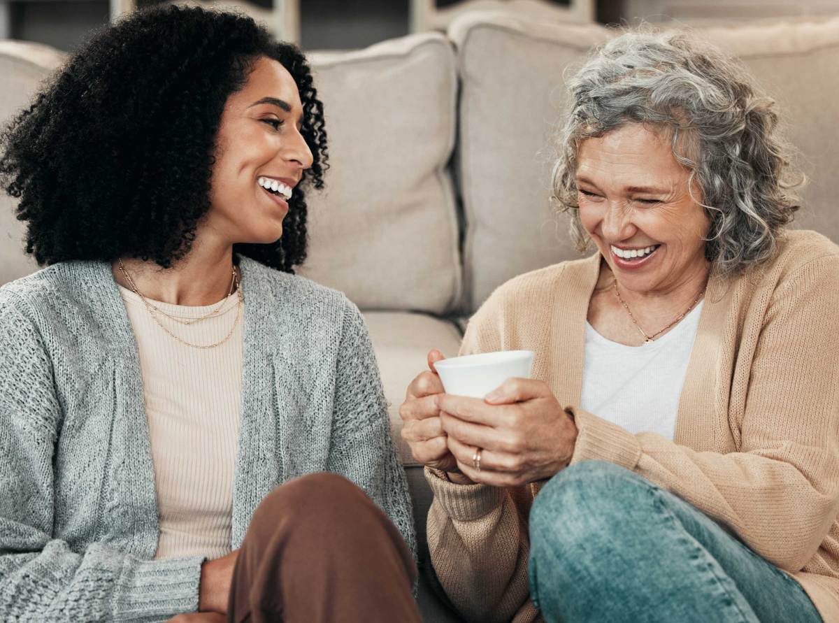 Liebe, Mutter und erwachsene Tochter auf dem Boden, Kaffee und Gespräch mit Glück, Pause und Lachen.