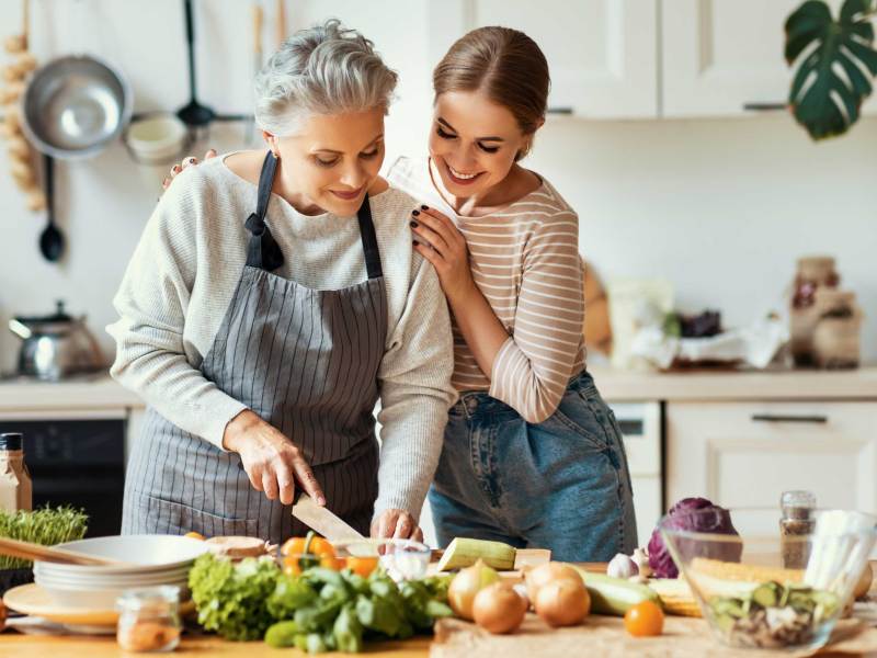 Glückliche Mutter und Tochter bereiten zu Hause gesundes Essen zu