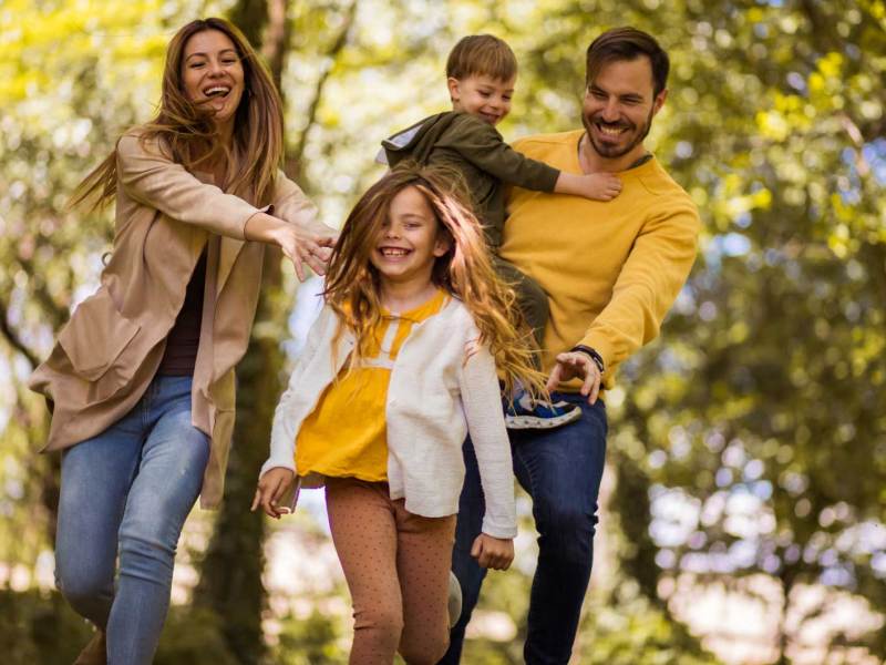 Vierköpfige Familie hat Spaß bei einem herbstlichen Waldspaziergang.