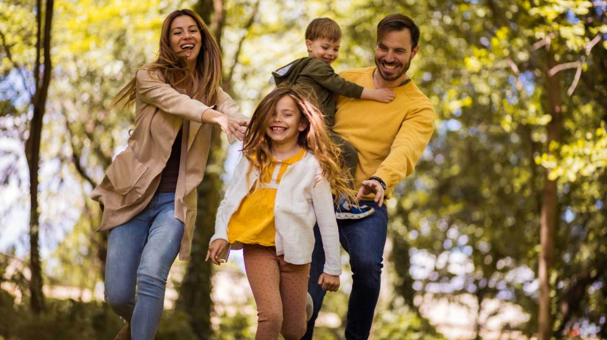 Vierköpfige Familie hat Spaß bei einem herbstlichen Waldspaziergang.