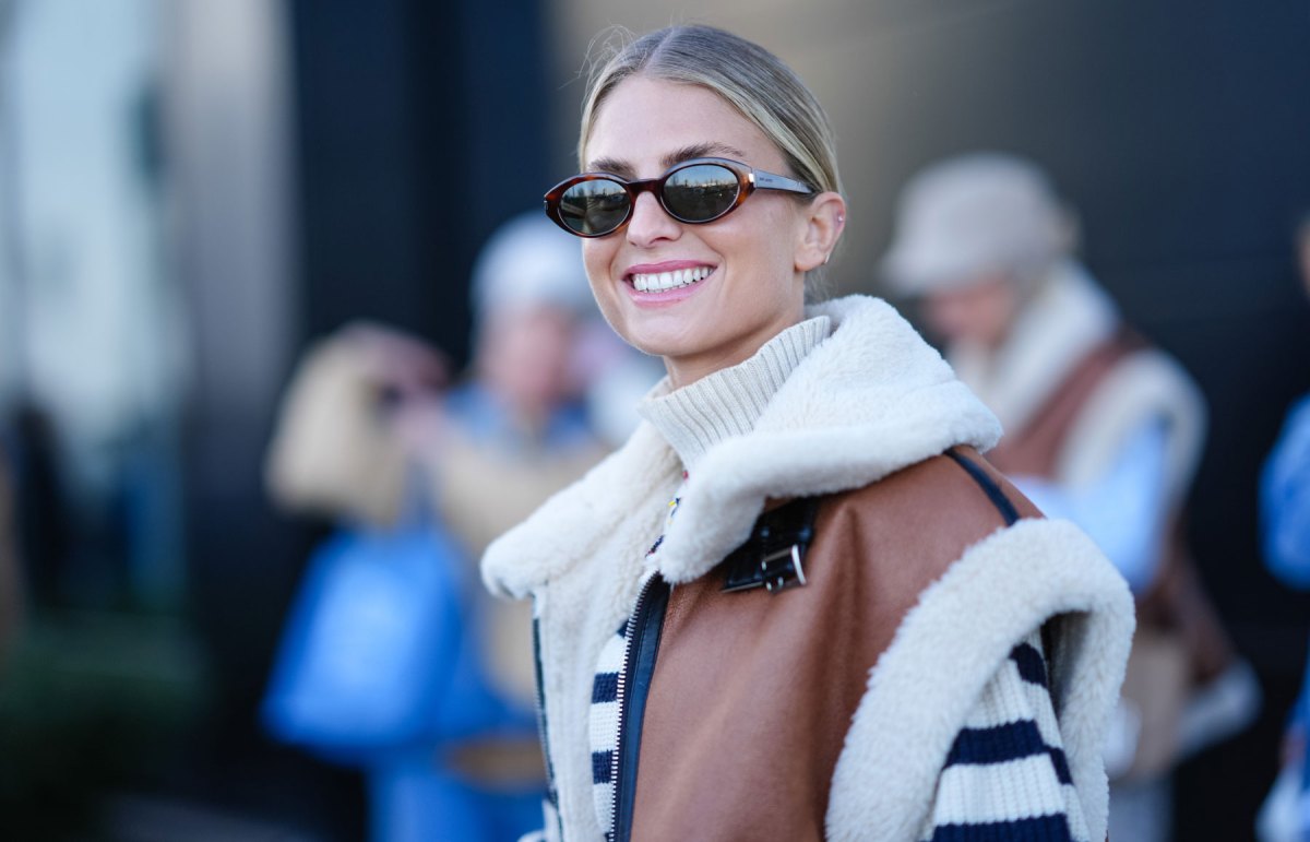 Frau mit Sonnenbrille lächelt und trägt Fellweste