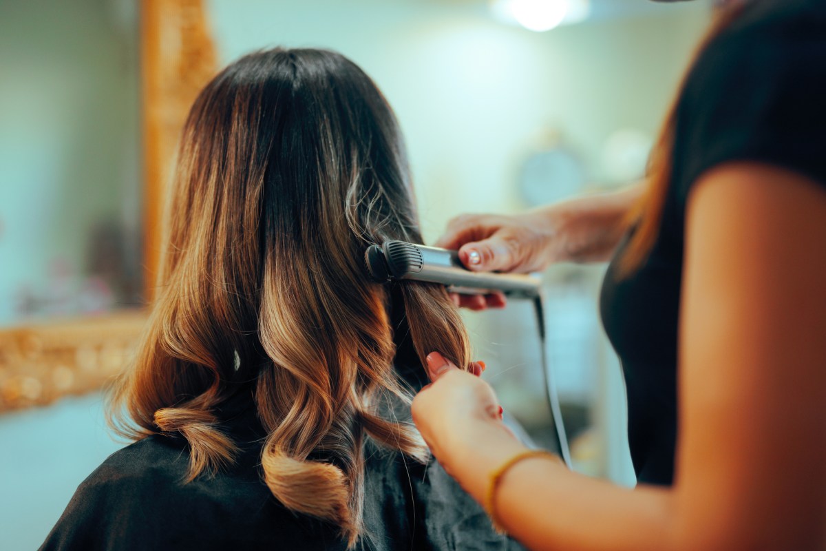 Frau bekommt Locken mit dem Glätteisen gemacht