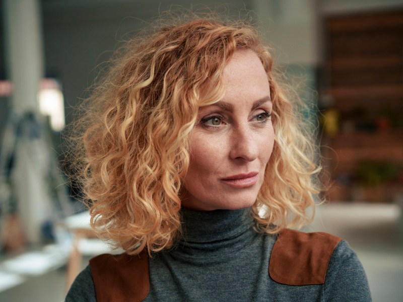 Frau mit lockigem blonden Haar schaut nachdenklich als Symbolbild für Sternzeichen Fische