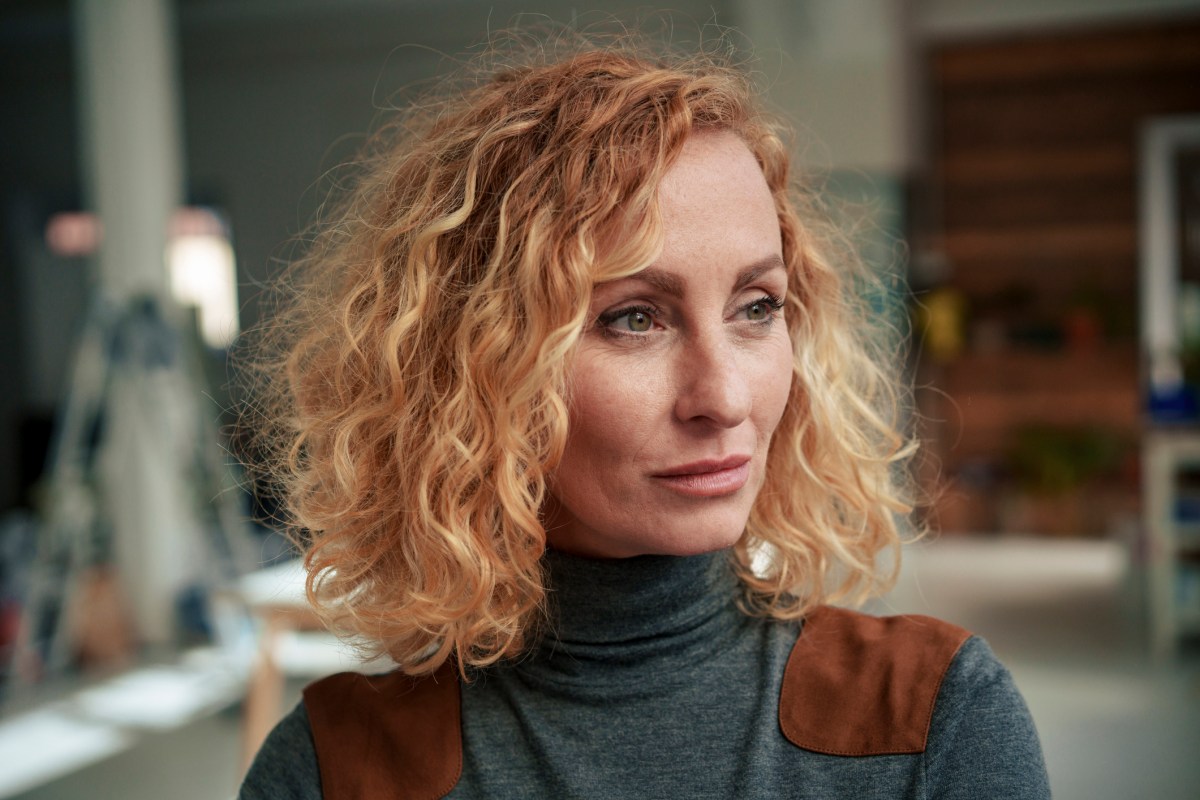 Frau mit lockigem blonden Haar schaut nachdenklich als Symbolbild für Sternzeichen Fische