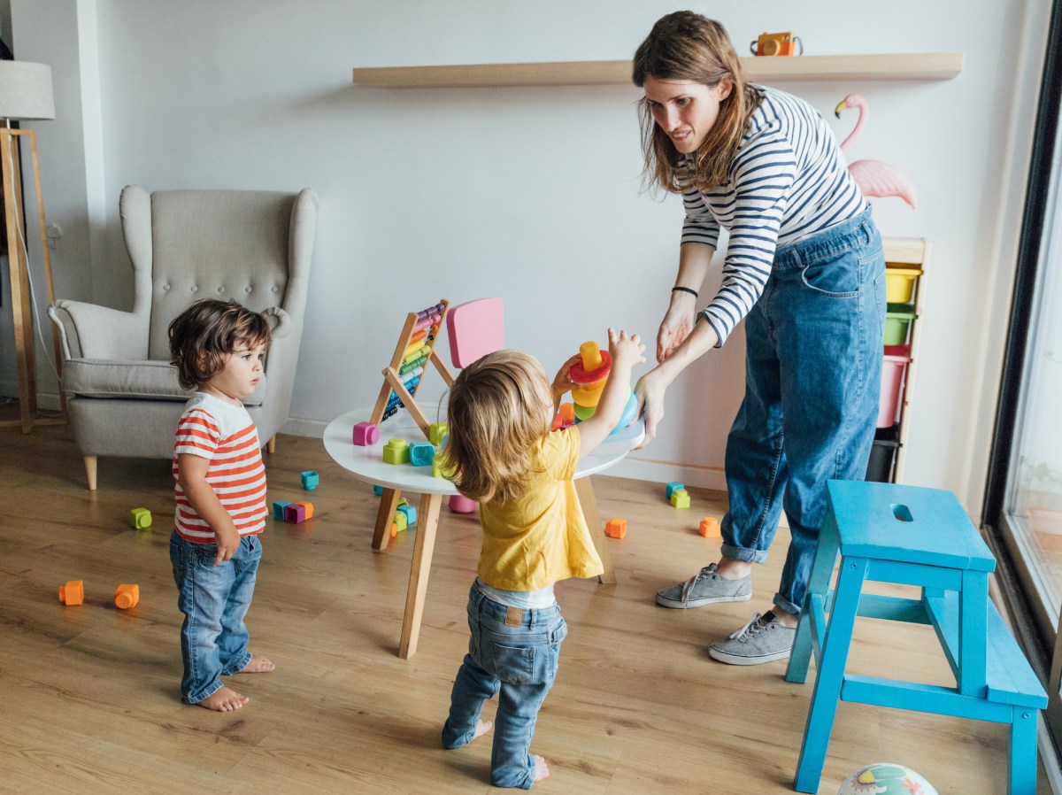 Frau mit zwei Kindern in Kinderzimmer