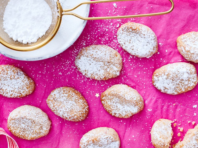 Kleine Kekse, die wie Mini-Christstollen aussehen auf pinkem Untergrund.