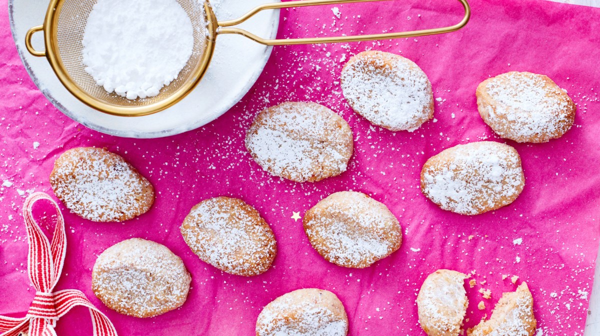 Kleine Kekse, die wie Mini-Christstollen aussehen auf pinkem Untergrund.