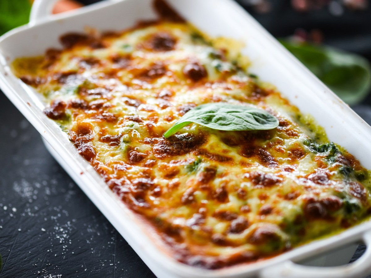 Lasagne mit Spinat in einer weißen Auflaufform.