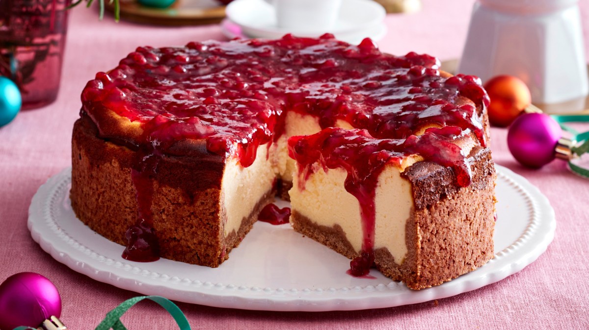 Käsekuchen mit Preiselbeer-Topping auf einem weißen Teller.